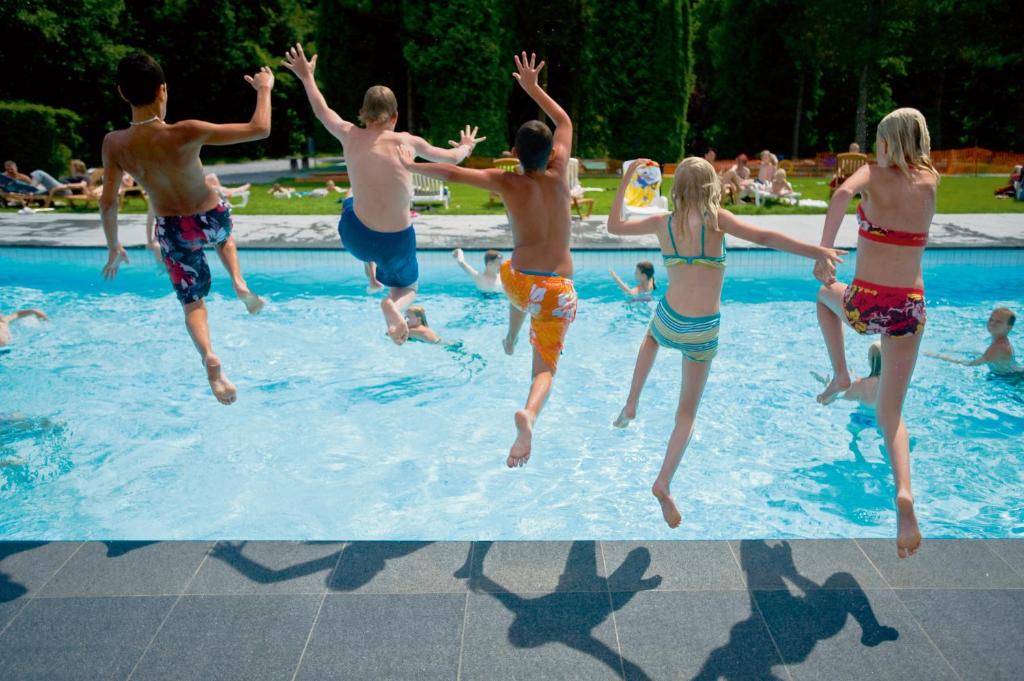 a group of people jumping into a swimming pool at Domaine Long Pre in Stavelot