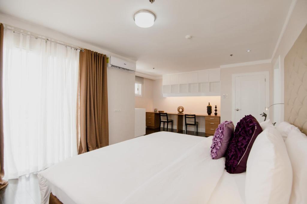 a bedroom with a large white bed with purple pillows at Sta Barbara Residence Hotel in Cebu City