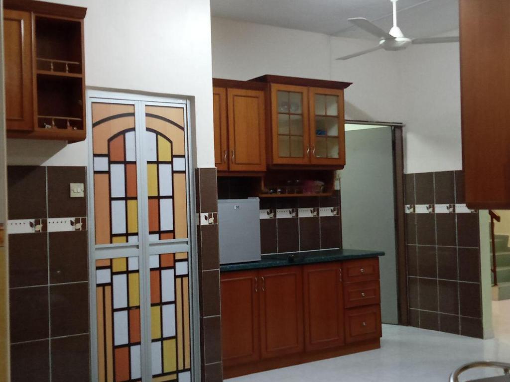 a kitchen with wooden cabinets and a glass door at Muslim Homestay Ustaz 2 in Taiping