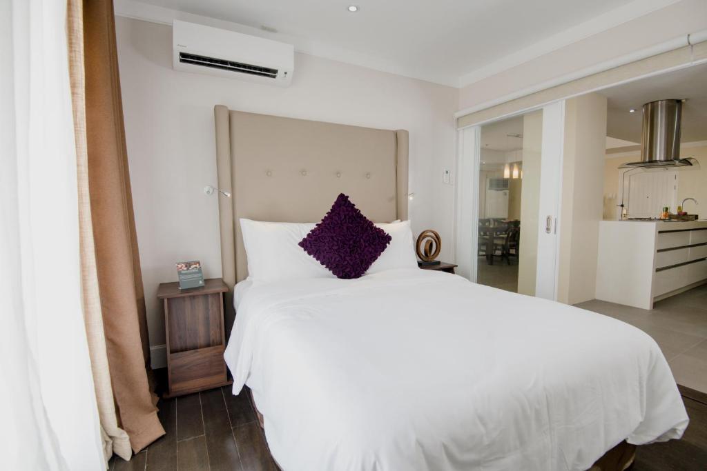 a bedroom with a large white bed with purple pillows at Sta Barbara Residence Hotel in Cebu City