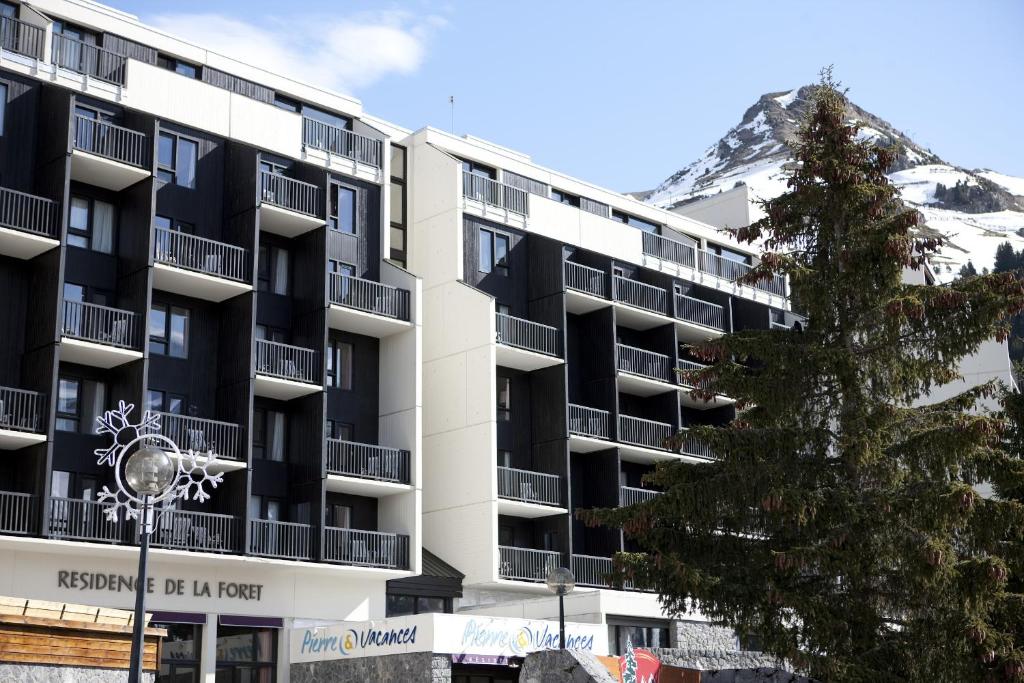 ein Apartmenthaus mit einem schneebedeckten Berg im Hintergrund in der Unterkunft Residence La Foret - maeva Home in Arâches-la-Frasse