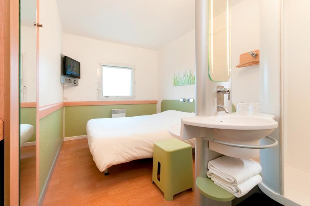 een ziekenhuiskamer met een bed en een wastafel bij ibis budget Brugge Centrum Station in Brugge