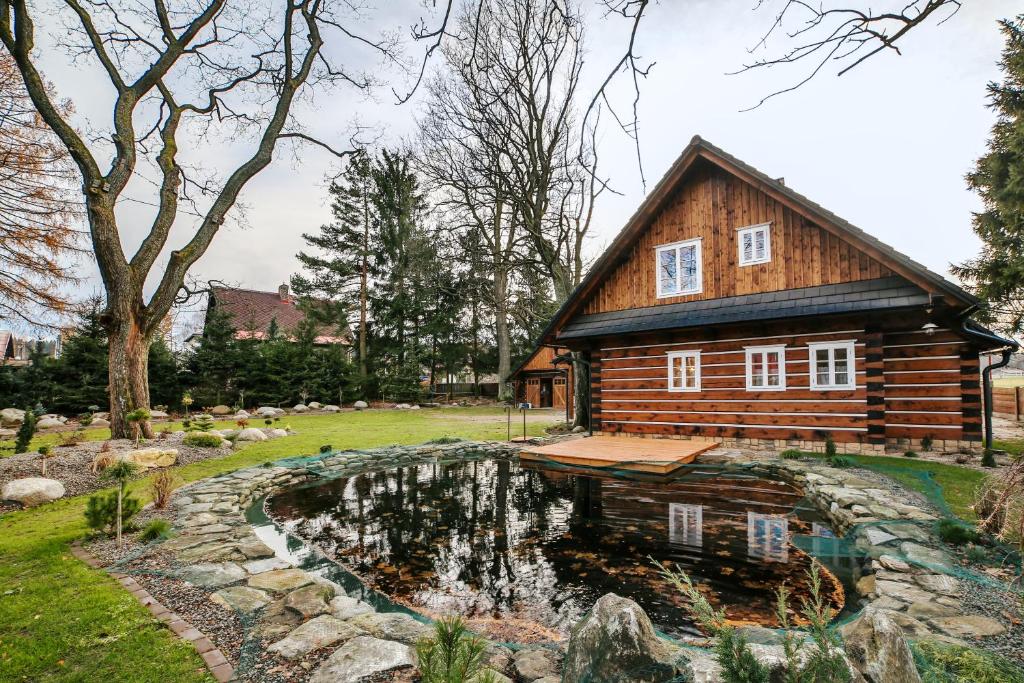 eine Blockhütte mit einem Teich vor einem Haus in der Unterkunft Roubenka Štěpánka in Svratka