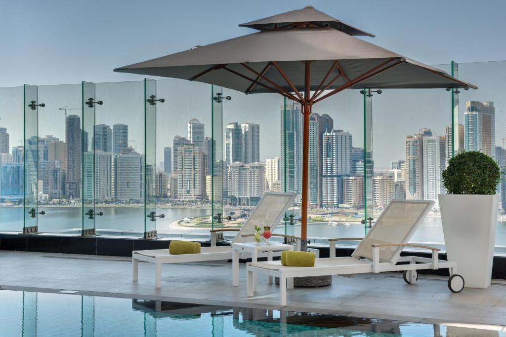 a patio with a table and chairs and an umbrella at The Act Hotel Sharjah in Sharjah