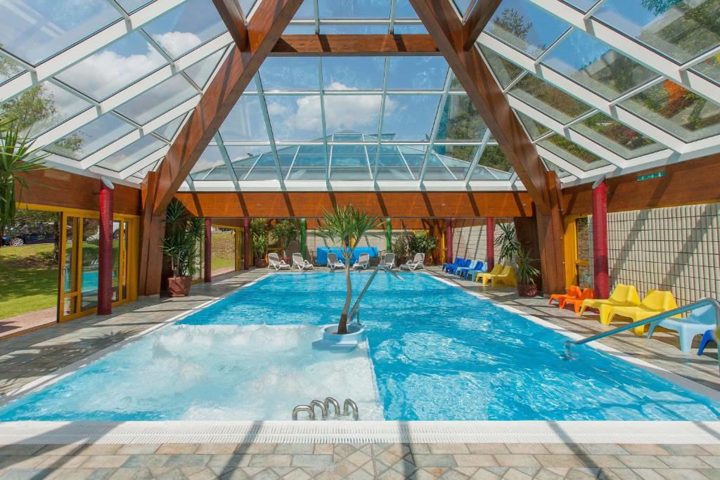 an indoor swimming pool with a glass ceiling at Grand Hotel Gortani in Arta Terme