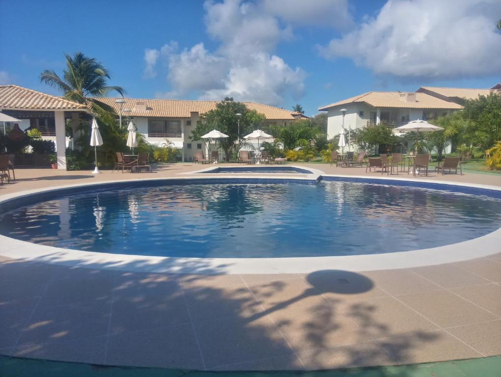 a swimming pool in a resort with chairs and umbrellas at Apto. Vila dos Lírios - Reserva Imbassai in Imbassai