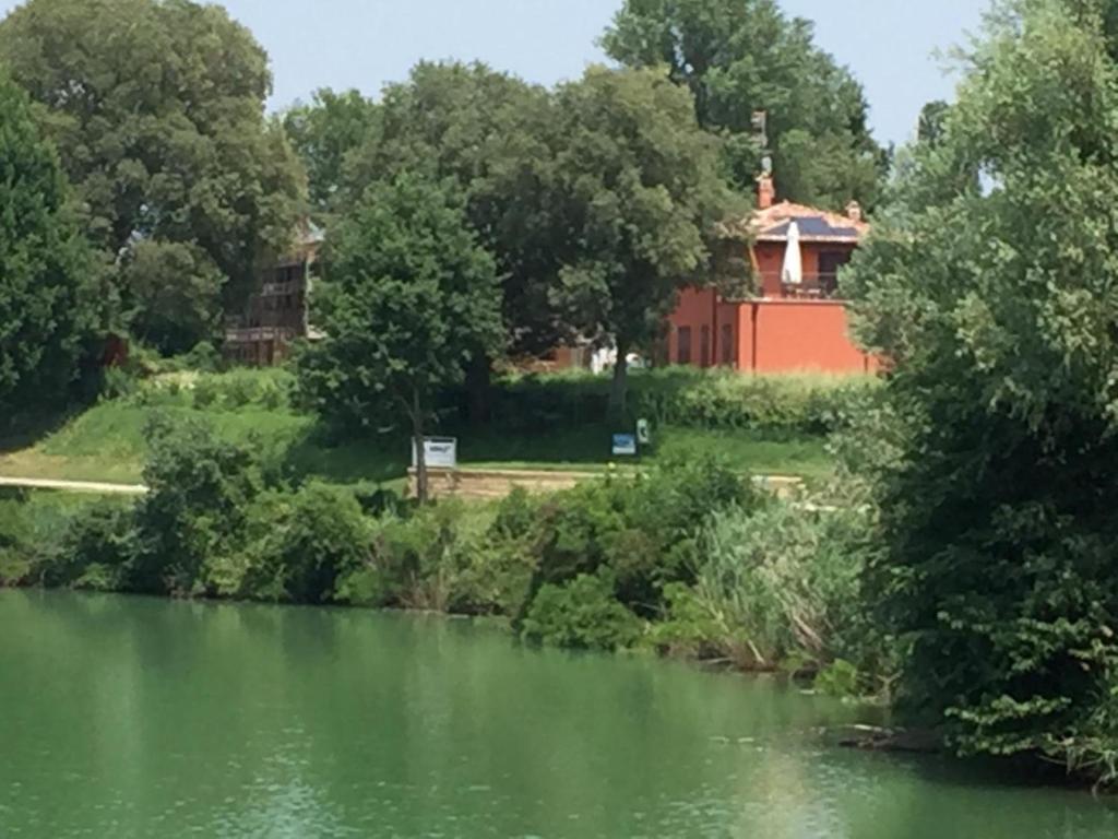 a red building next to a river with trees at B&B Hole6 in Castenaso