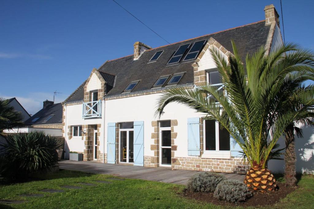 een wit huis met een palmboom ervoor bij Maison familiale-Surf House, plage de Sainte Barbe in Plouharnel