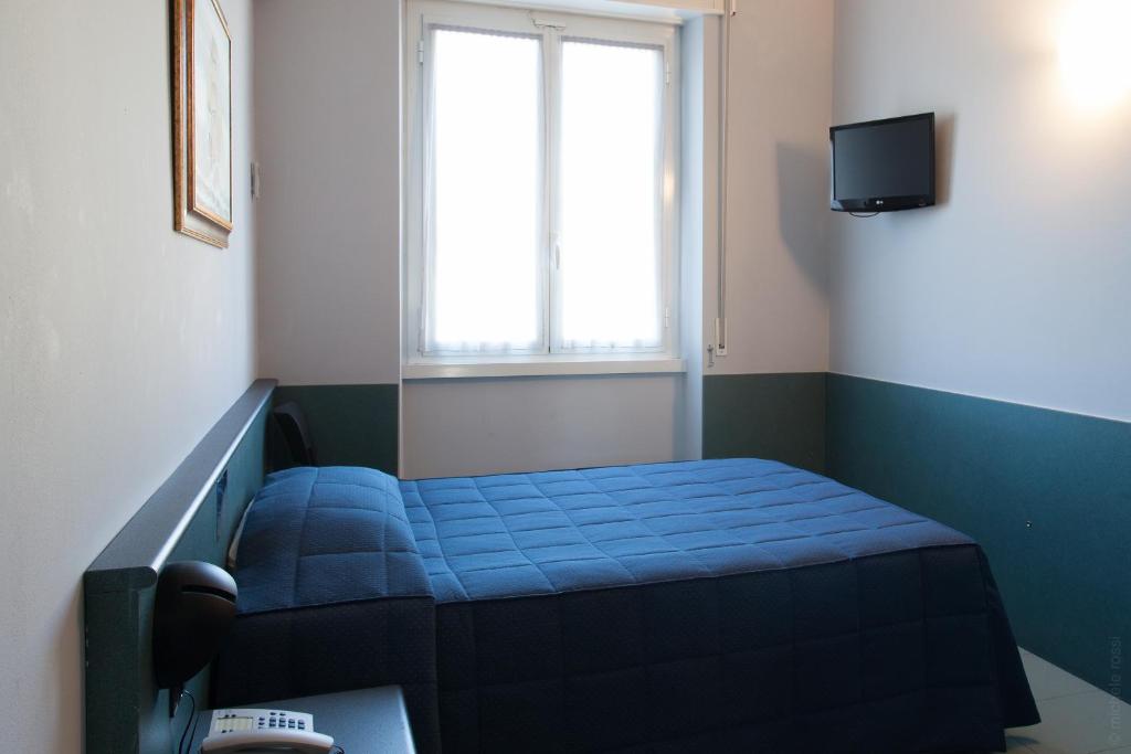 a small room with a blue bed and a window at Hotel Tirreno in Genoa