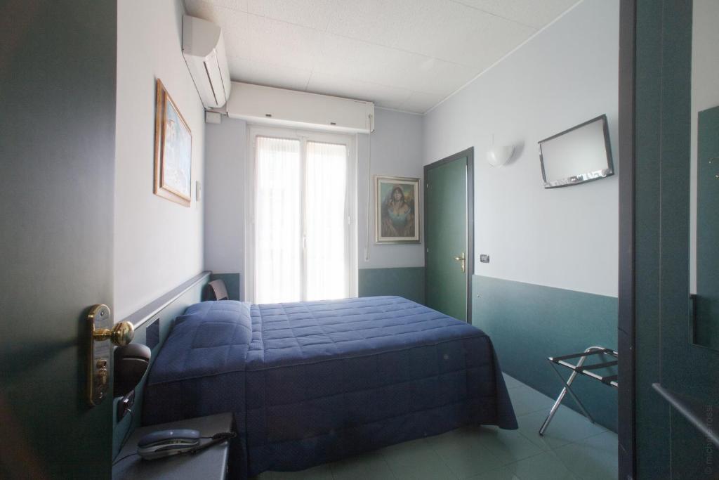 a bedroom with a blue bed and a window at Hotel Tirreno in Genoa