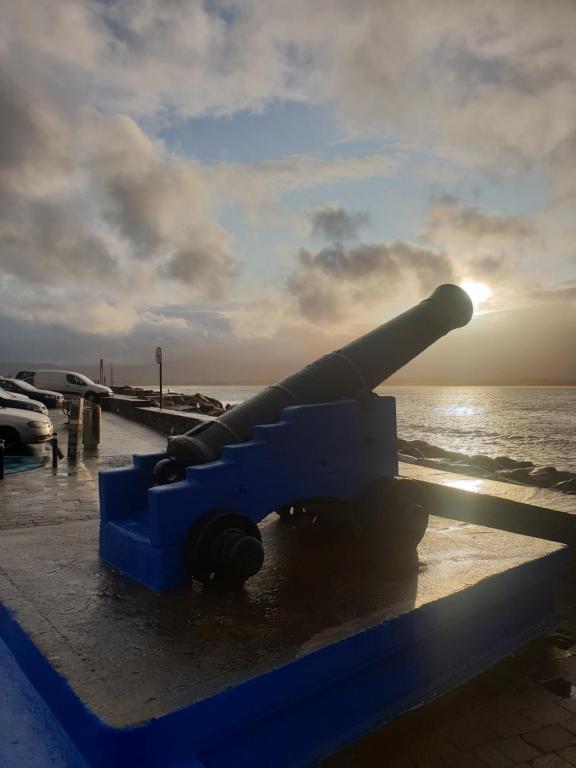 a cannon sitting on a bench next to the ocean at Surfers Getaway - Room Staycation in Sligo