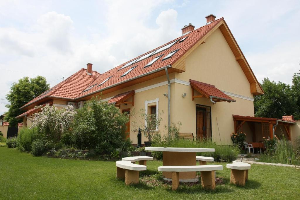 una casa con una mesa y bancos en el patio en Élet es Energia Egészségjavító Szalon, en Nagykőrös