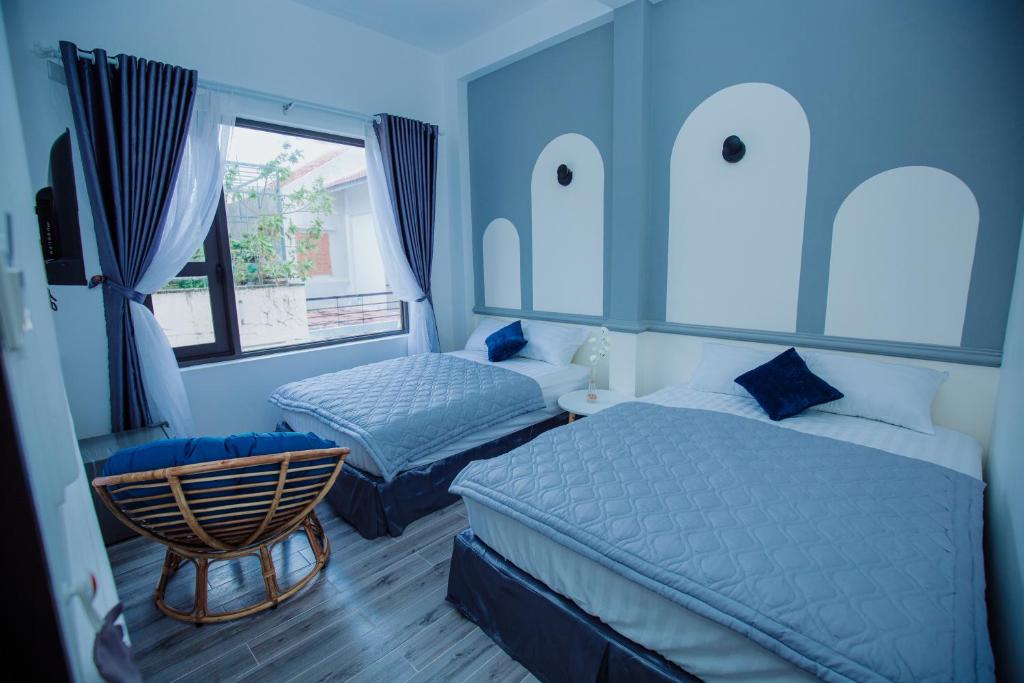 a blue bedroom with two beds and a chair at Rome Hostel in Tuy Hoa