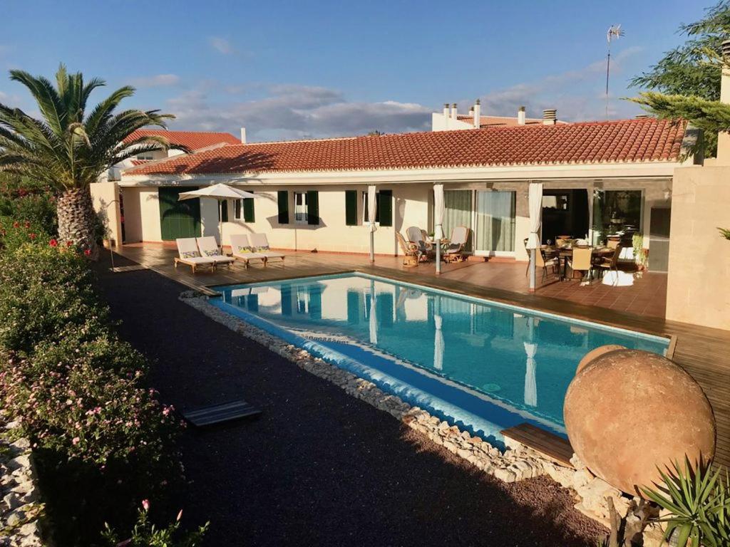 a swimming pool in front of a house at Villa Victoria in Sa Caleta