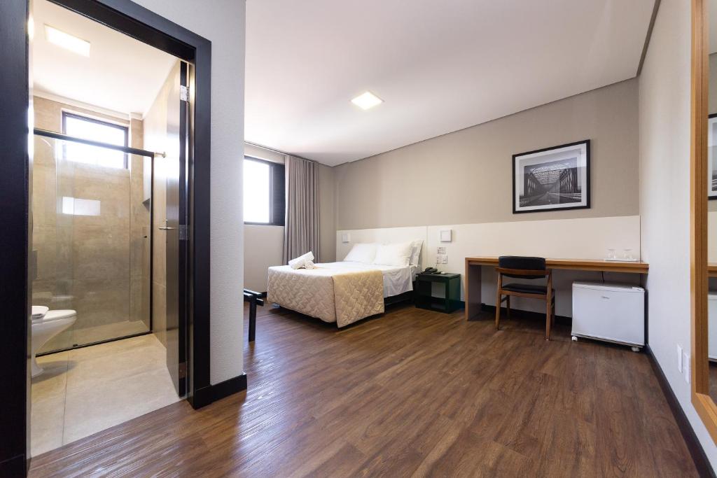 a hotel room with a bed and a desk and a bathroom at Hotel Lunes in São José