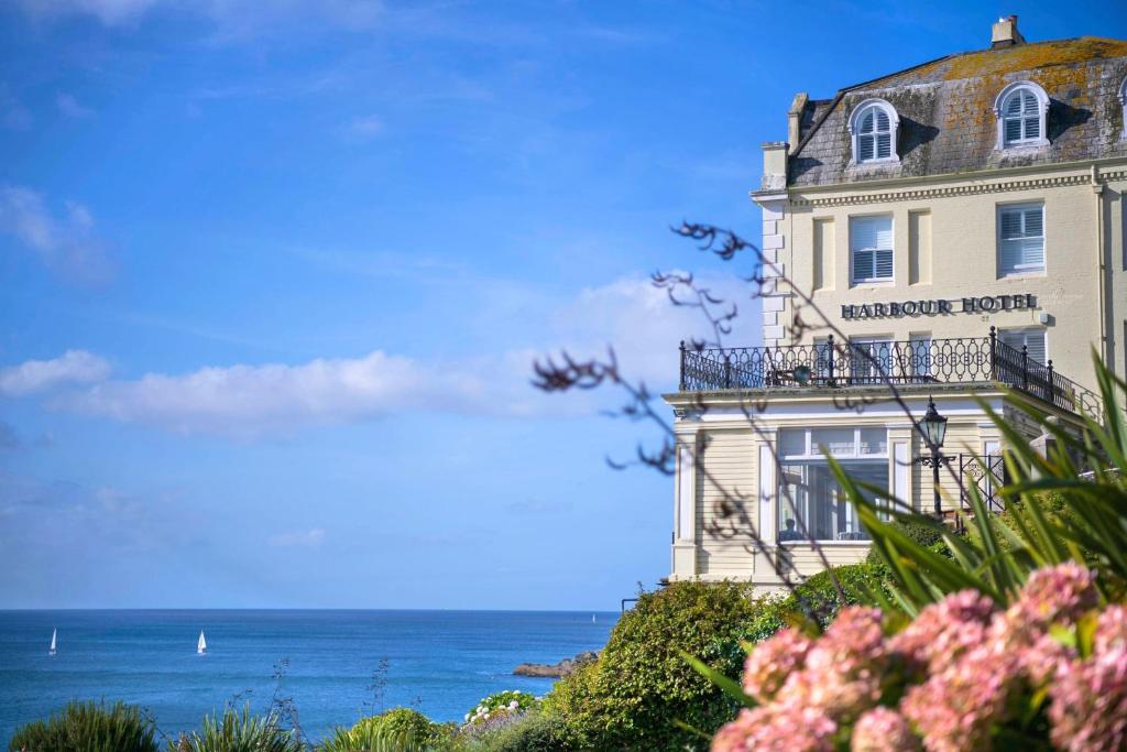 a building on a hill with the ocean in the background at Harbour Hotel Fowey in Fowey