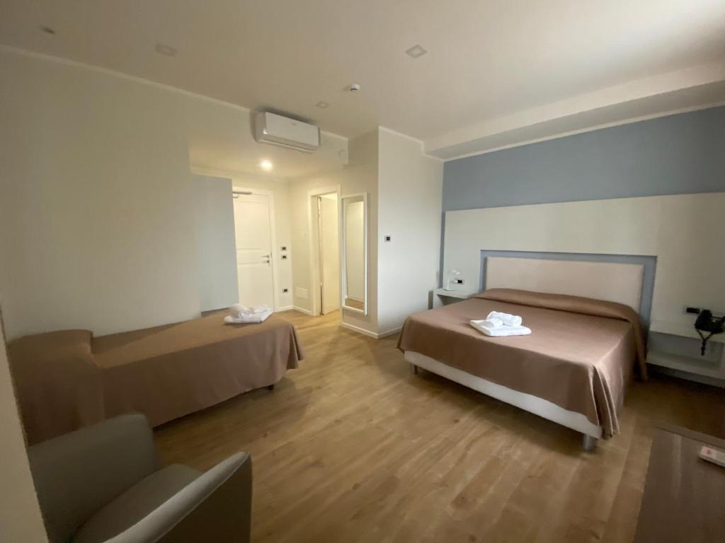 een hotelkamer met 2 bedden en een stoel bij La Porta del Sole Hotel & Village in San Ferdinando