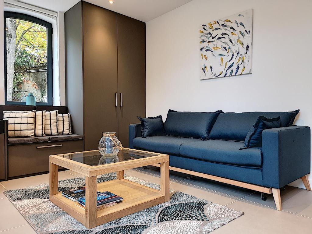 a living room with a blue couch and a table at La Viralamande by Cocoonr in Crépieux-la-Pape