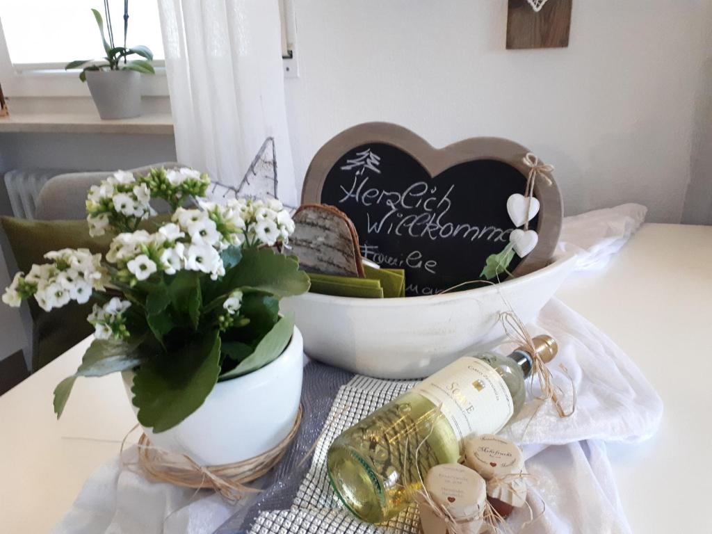 a table with a bowl of flowers and a bottle of wine at Dorfliebe in Oy-Mittelberg