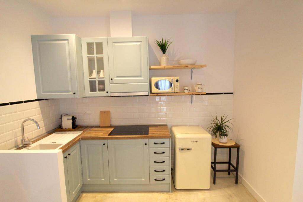 a kitchen with white cabinets and a white refrigerator at Loft Alguer en Ametlla de Mar in L'Ametlla de Mar