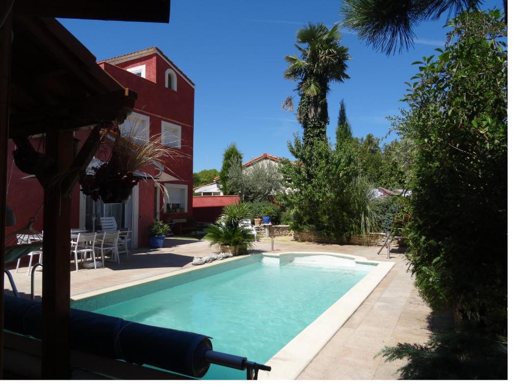 uma piscina em frente a uma casa com uma palmeira em REDHOUSE Studio Zen em Roques Sur Garonne