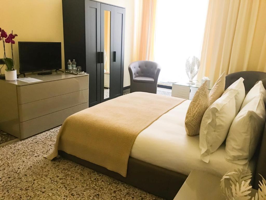 een slaapkamer met een groot bed en een televisie bij BASILICO Genova in Genua