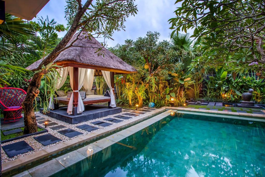 a swimming pool with a gazebo next to a villa at Tiga Samudra Villa in Canggu