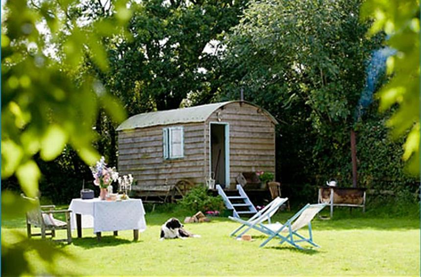 a table and chairs in front of a small shed at Mollies Hut in Frome