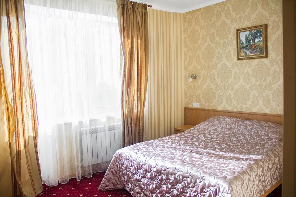 1 dormitorio con cama y ventana grande en Guest House PARTIA, en Stavropol