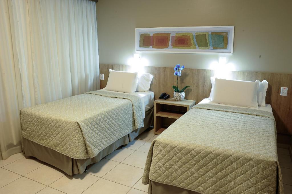 a hotel room with two beds and two lamps at Plaza Inn Augustus in Goiânia