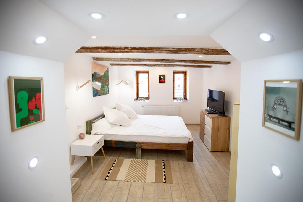 ブラショヴにあるBrasha Residenceのベッドとテレビのある白い寝室