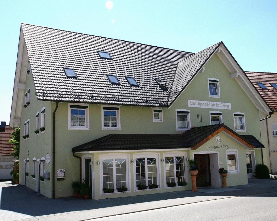 ein großes grünes Gebäude mit schwarzem Dach in der Unterkunft Landgasthof Bieg in Neuler