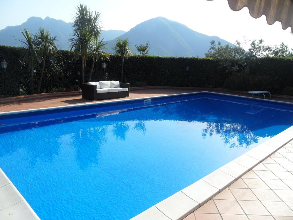 a large blue swimming pool with a couch and palm trees at Lady Food Location in Cava deʼ Tirreni