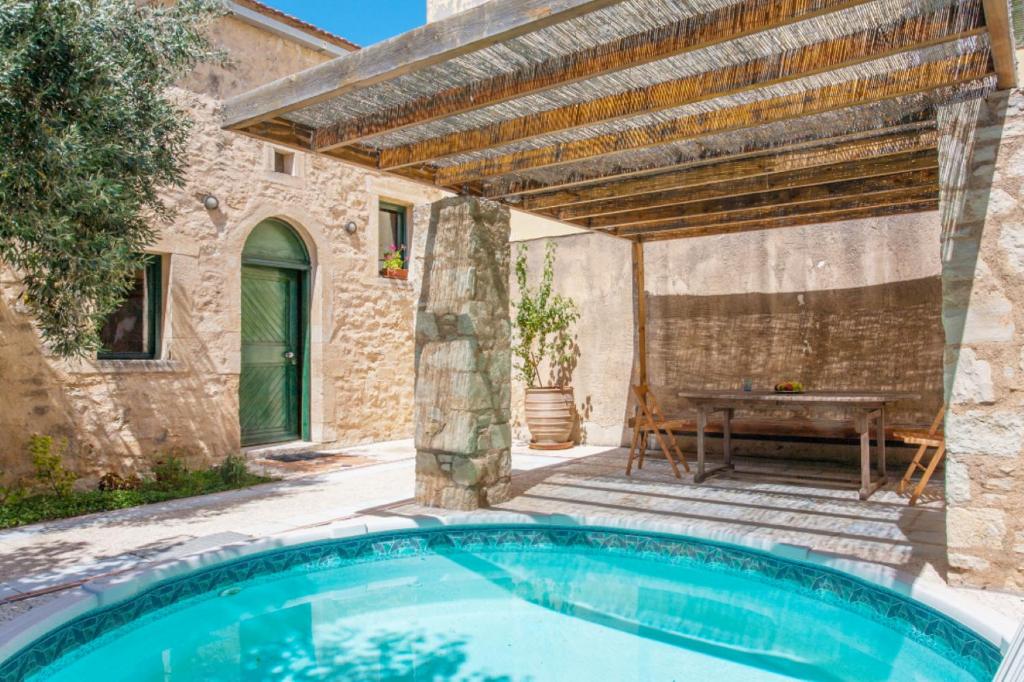 una piscina frente a una casa con pérgola en Milio's House en Roústika
