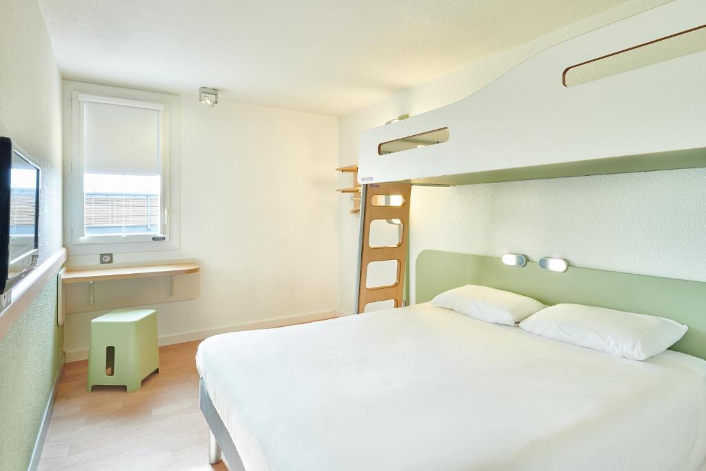 une chambre avec un grand lit blanc et une fenêtre dans l'établissement ibis budget Saint Paul Les Dax, à Saint-Paul-lès-Dax