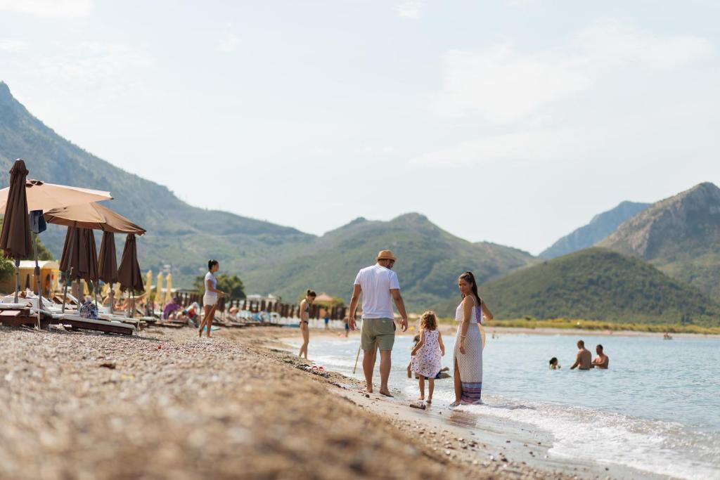 a group of people walking on a beach at Hotel Savojo in Petrovac na Moru