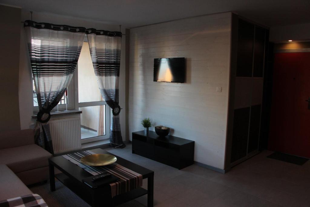 een woonkamer met een tafel en 2 ramen bij Apartament Jagiellońska 70 in Bydgoszcz