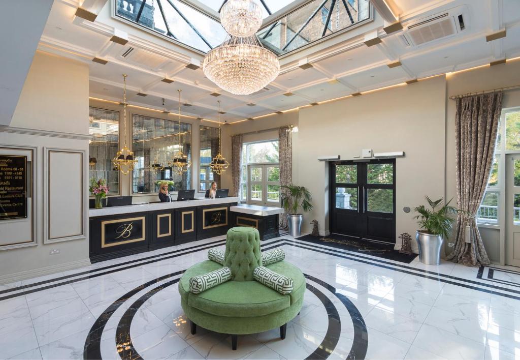 a large lobby with a green chair and a table at Bonnington Hotel & Leisure Centre in Dublin