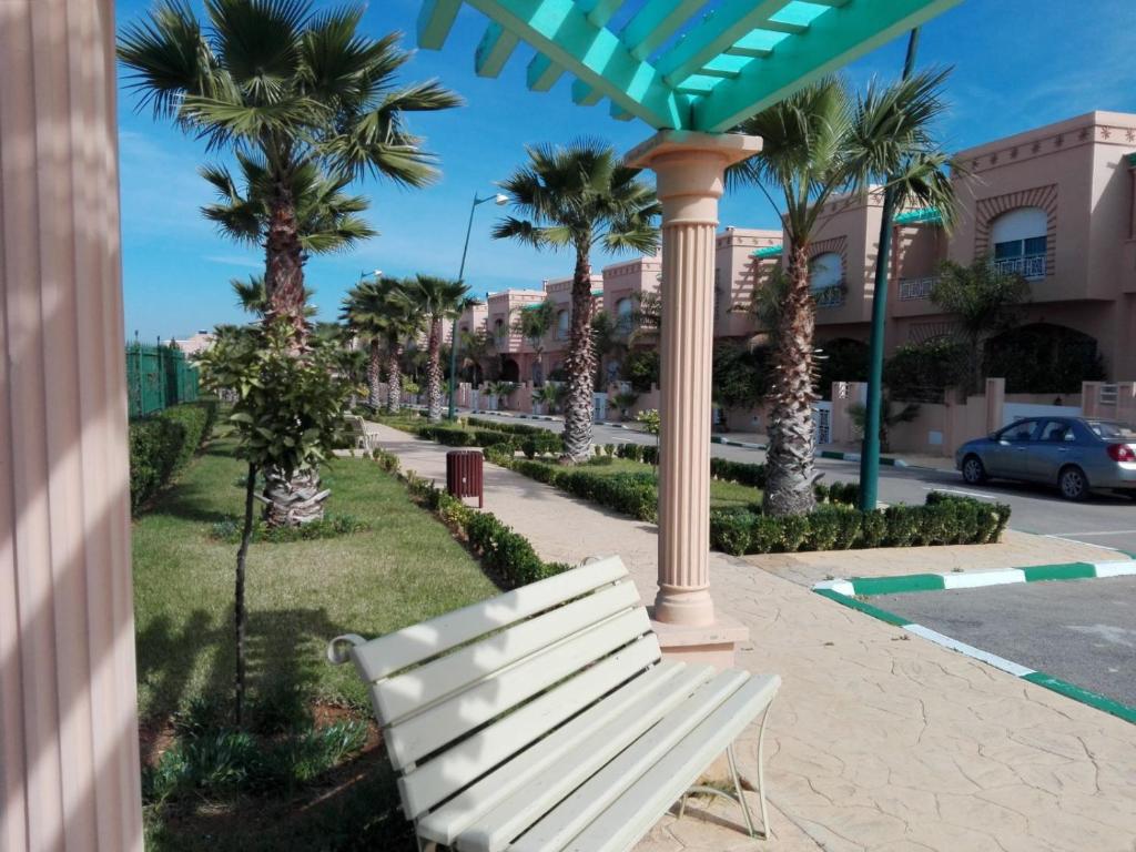 eine weiße Bank auf einem Bürgersteig neben Palmen in der Unterkunft Villa Fatima in Meknès