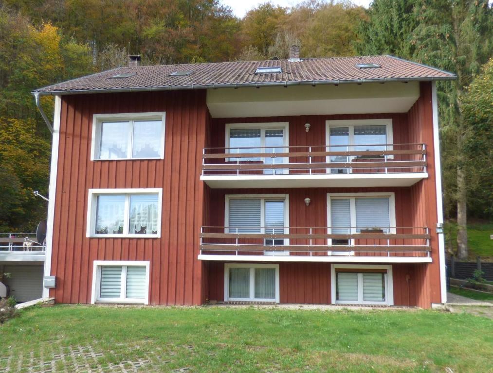una casa rossa con balconi sul lato di FeWo direkt am Wald und Wanderweg mit Balkon Ruhe pur 1 OG a Bad Sachsa