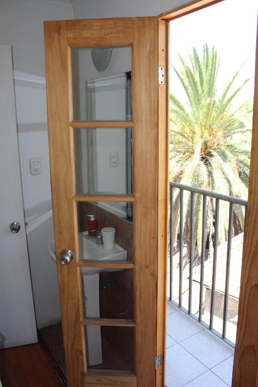 a door to a balcony with a view of a palm tree at Aji Hostel in Santiago