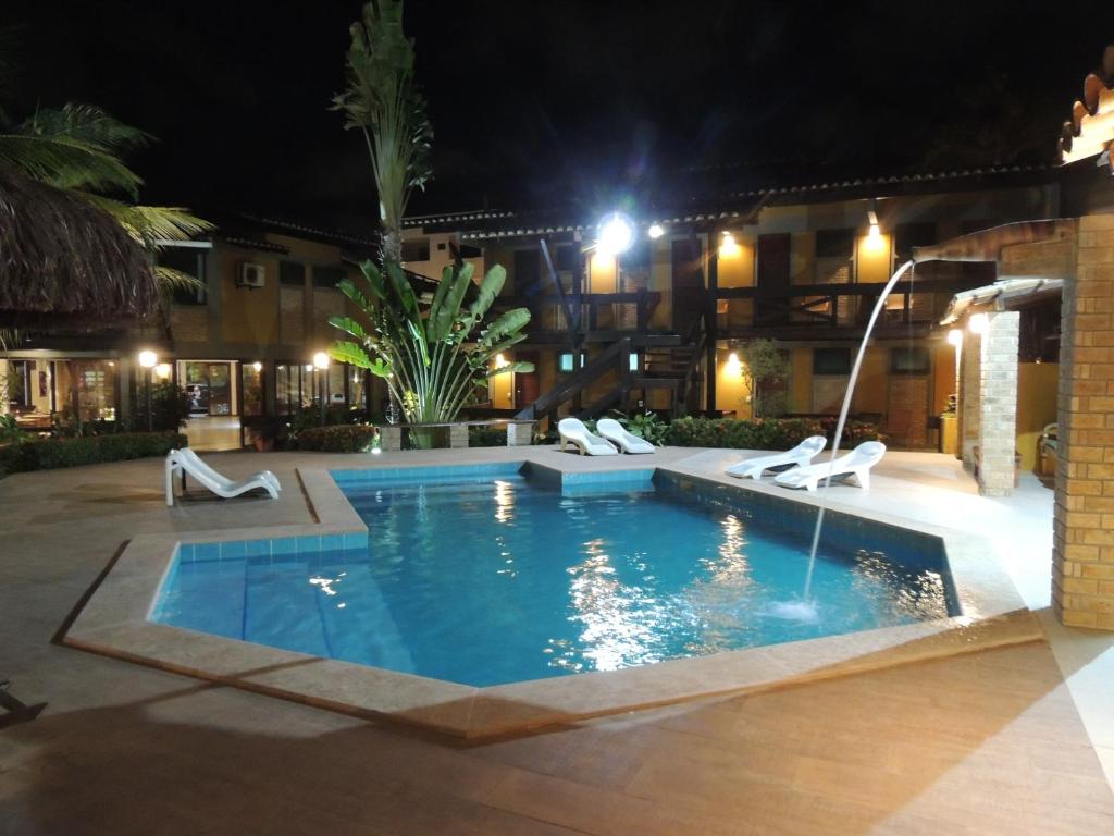 a swimming pool at night with chairs around it at Marinas Pousada in Ilhéus