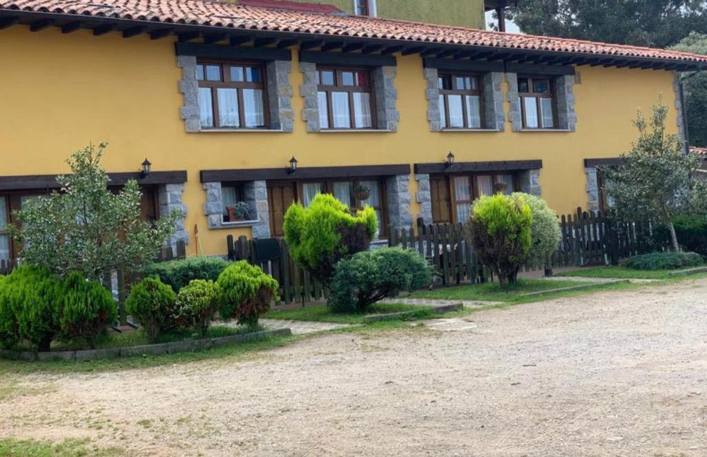 una casa gialla con una recinzione di fronte di APARTAMENTOS MARIAJE a Barro de Llanes