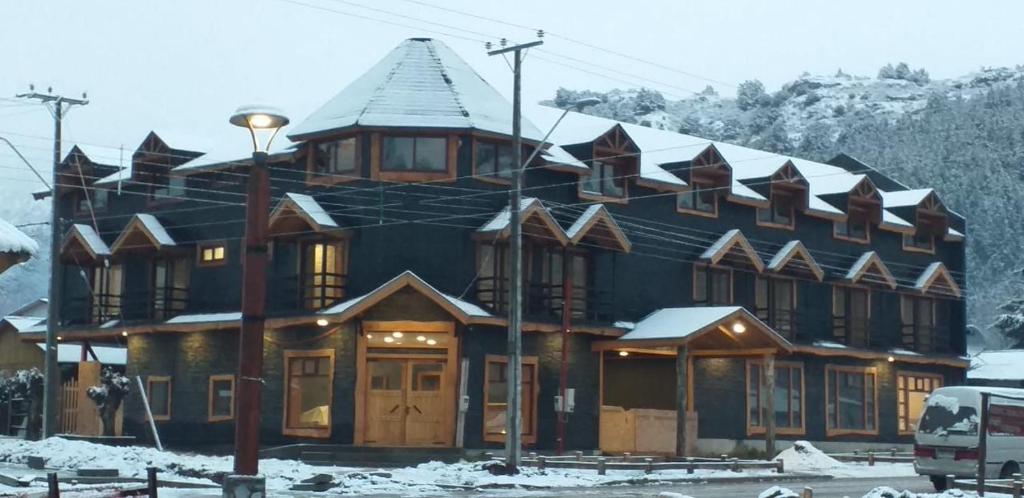 a large building with snow on the roof at Apart Hotel y Cabañas Valle Exploradores in Puerto Tranquilo