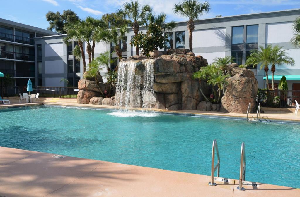 a swimming pool with a waterfall in front of a building at Opal Hotel & Suites in Orlando