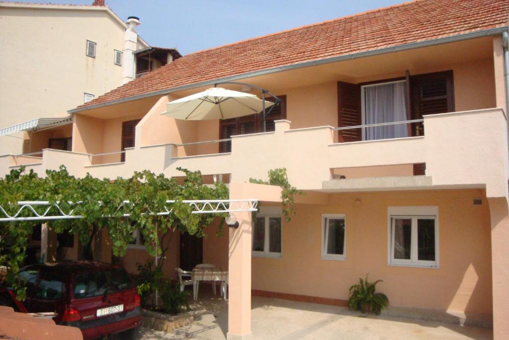 a house with an umbrella in front of it at Apartments Pavlov in Tisno