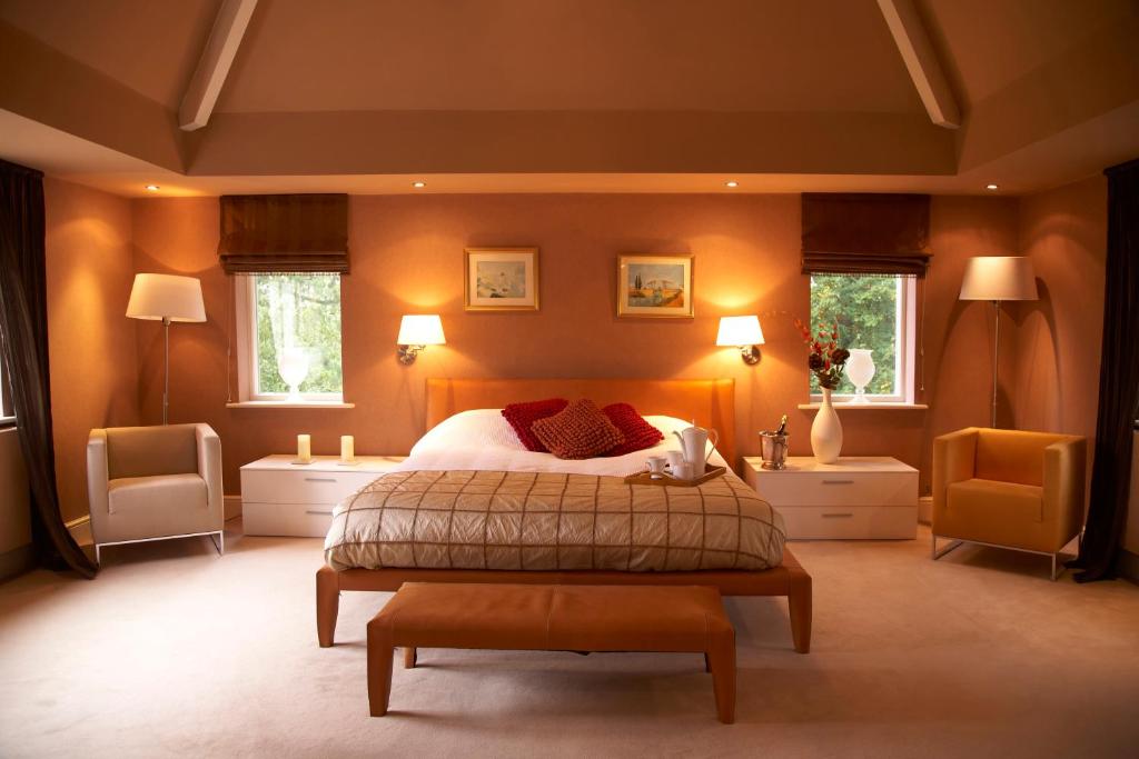 a bedroom with a large bed and two chairs at Halliwell House Boutique in Hale