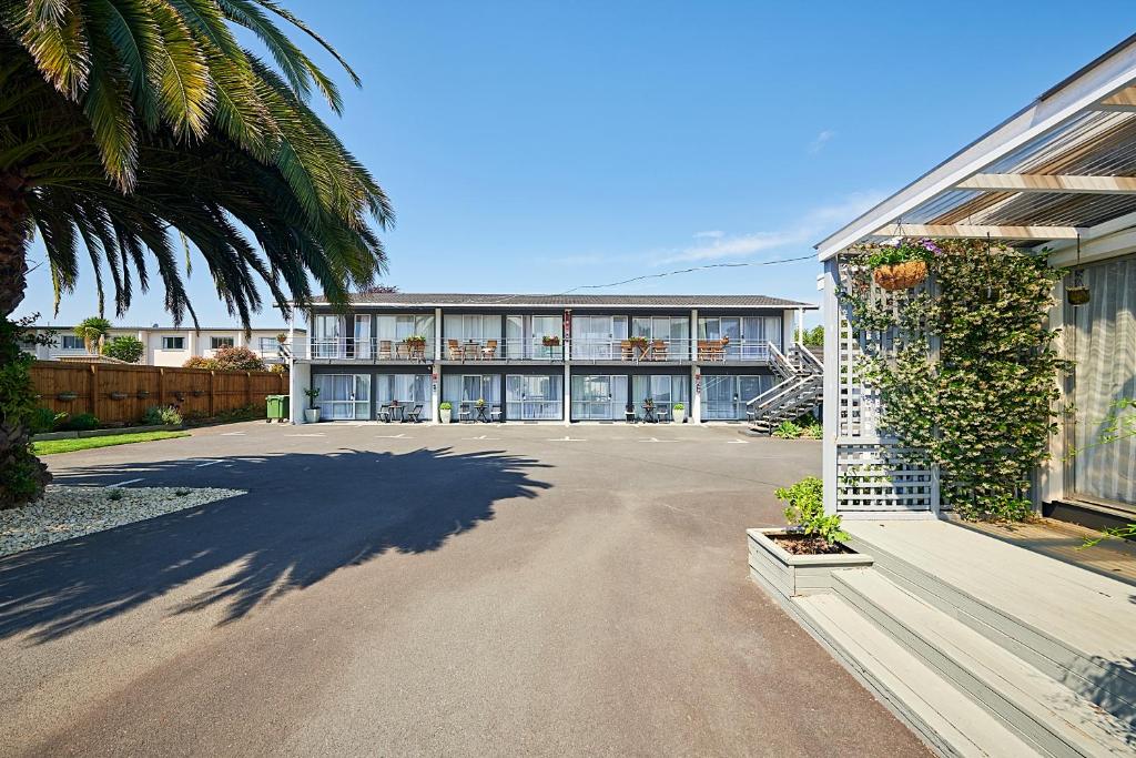 un gran edificio con una palmera y un camino de entrada en Roselands Motel, en Tauranga