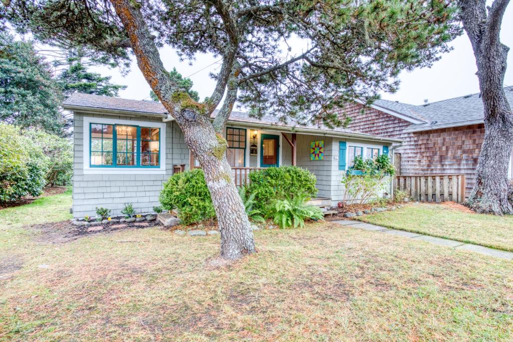 ein Haus mit einem Baum im Hof in der Unterkunft Seaside Classic Cozy Bungalow in Seaside