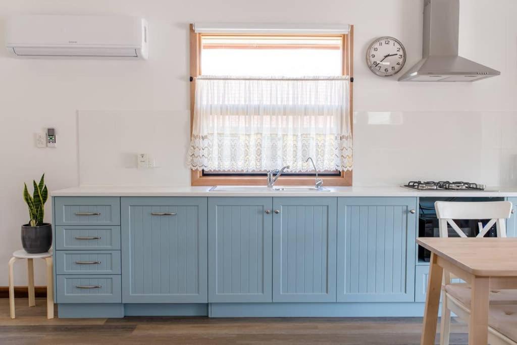 a kitchen with blue cabinets and a window at Bird In Hand Cottage, Port Noarlunga in Port Noarlunga